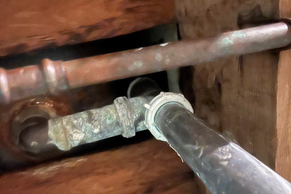 Corroded copper pipe joint inside an open wall